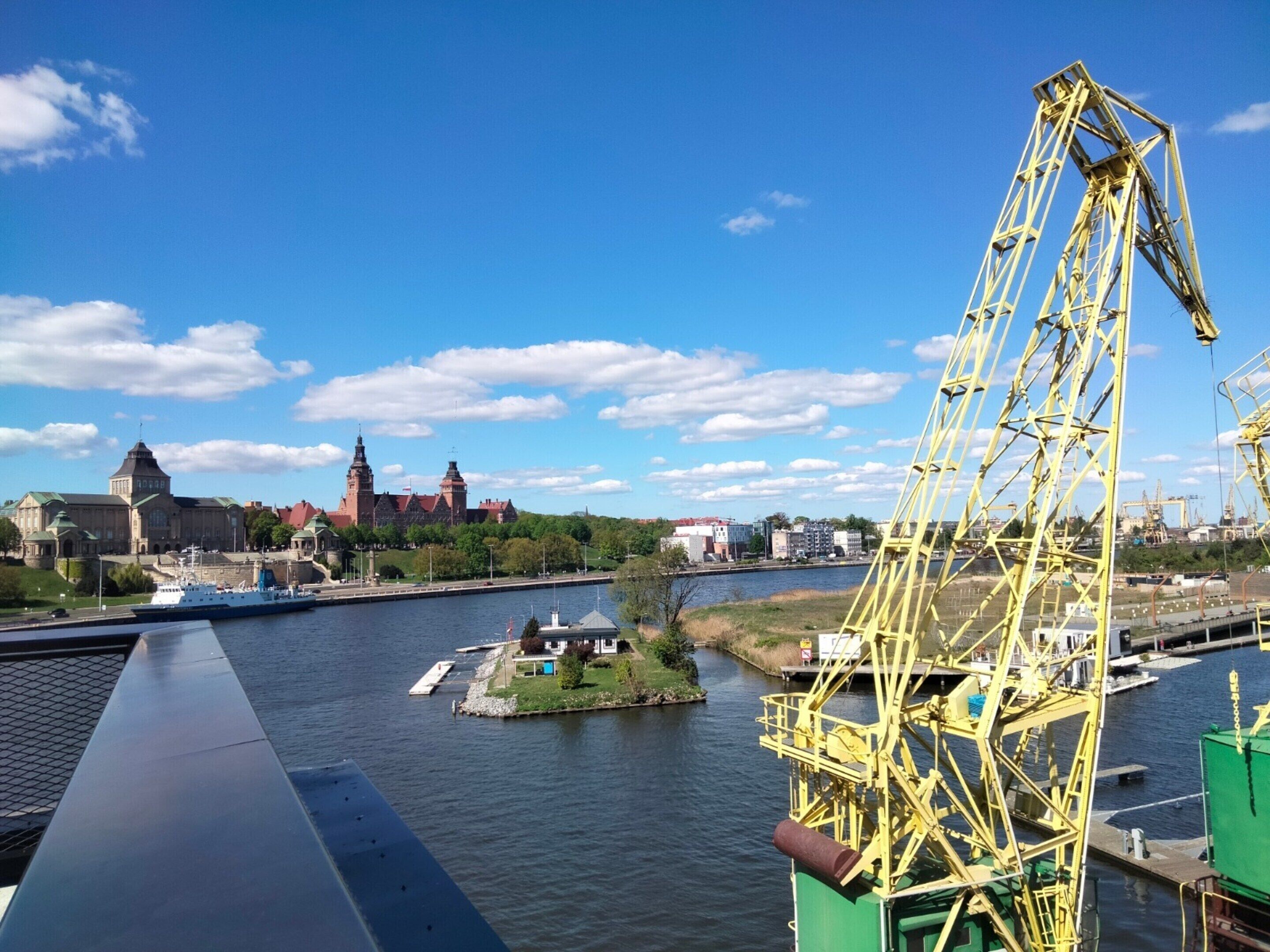A river with a bridge, a historic building, and a crane.