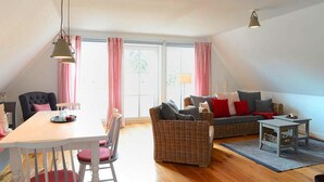 Ein gemütliches Wohnzimmer mit Esstisch, Rattan-Sofa und einem kleinen Beistelltisch.