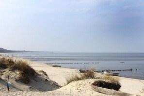 A beach with sand dunes, a boat, and wooden breakwaters in the water. - Gemutliches Ferienhaus in Zinnowitz, Ruhig Gelegen (Zinnowitz)