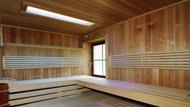 Eine Sauna mit Holzbänken und einem Dachfenster.