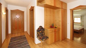 Ein gemütliches Schlafzimmer mit einem Holzschrank, einem kleinen Schreibtisch und einem farbenfrohen Stuhl.