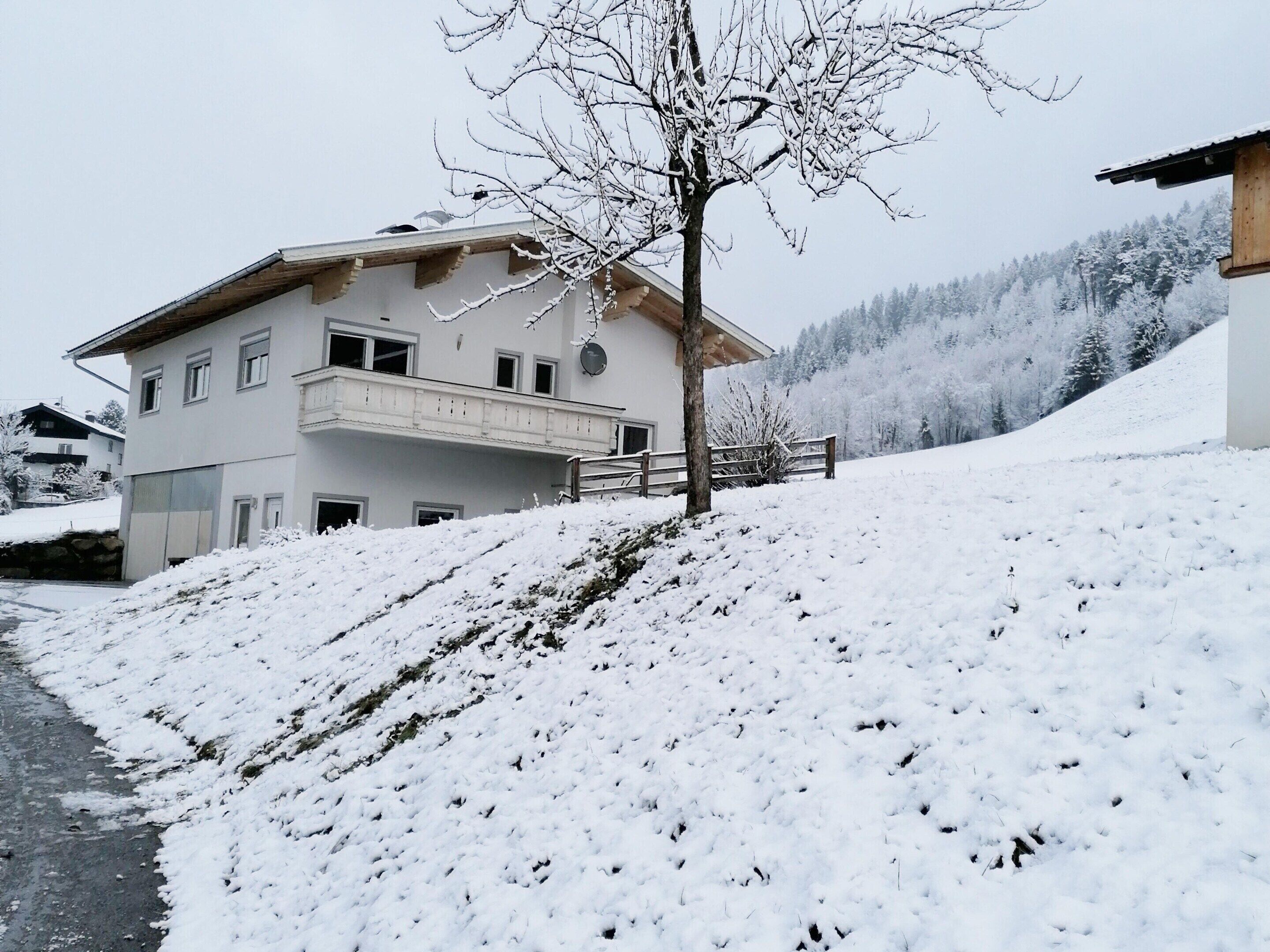 A two-story building with a balcony, surrounded by snow-covered ground and trees.