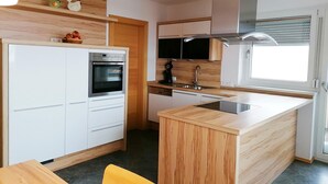Een moderne keuken met witte kasten, een inbouwoven, een magnetron, een spoelbak en een raam.