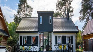 A two-story house with a tiled roof, a front porch with steps, and a paved driveway leading to the entrance. - Apartment in Jaroslawiec Near the Beach (Postomino)