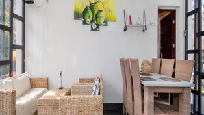 A cozy room with wicker furniture, a dining table, and a painting on the wall. - Apartment in Jaroslawiec Near the Beach (Postomino)