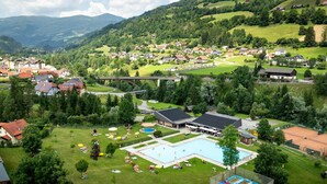 Zona residencial con piscina, canchas de tenis y un puente.