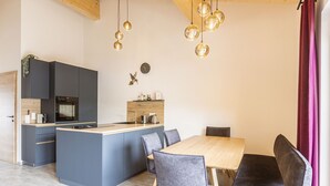 Eine moderne Küche mit grauen Schränken, einem Holztisch und grau bezogenen Stühlen.
