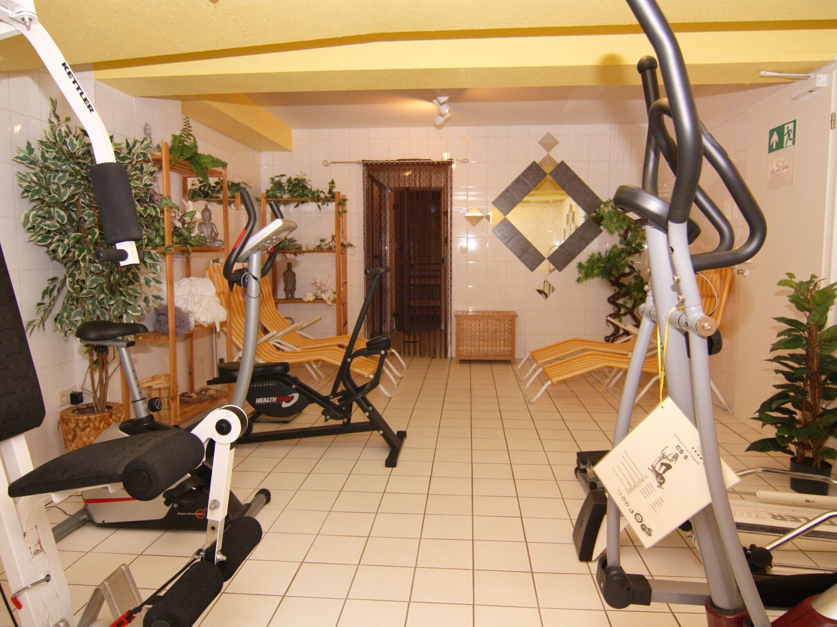 A gym with exercise equipment, including treadmills and stationary bikes, and a reception area with a door and a mirror.