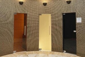 Un hall d’hôtel doté d’un sol circulaire en marbre, de trois portes et d’un mur à texture.