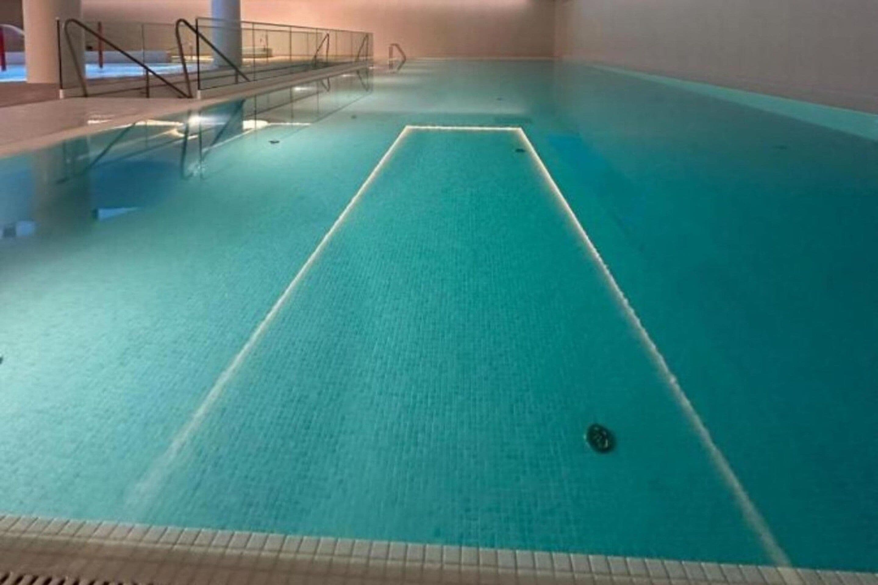 Une piscine intérieure à l’eau claire, dotée d’un plongeoir et d’un bloc de départ.