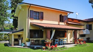 A two-story house with a patio, outdoor seating, and a garden. - Holiday Home Villa del Pino, Massarosa (Massarosa)
