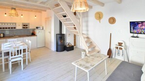 Una cocina moderna con muebles blancos, estufa integrada y zona de comedor con mesa y sillas blancas.