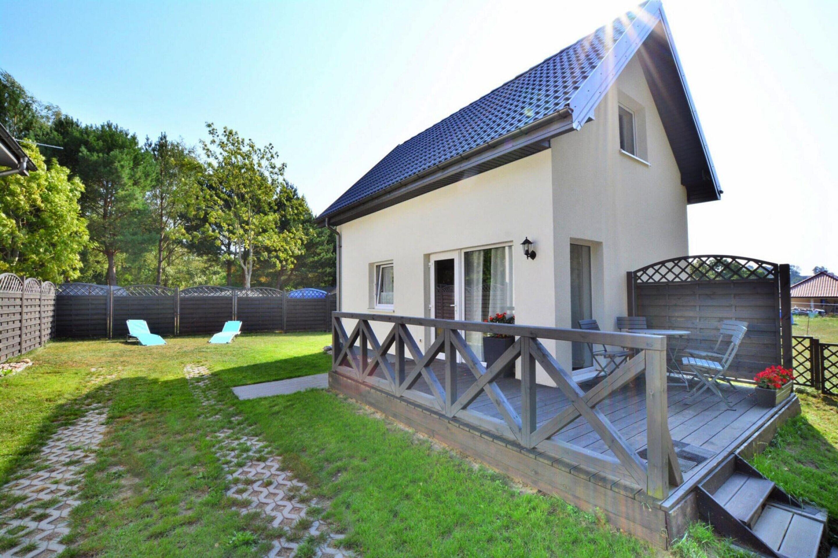 A house with a covered patio, a fenced backyard, and a small deck with chairs.
