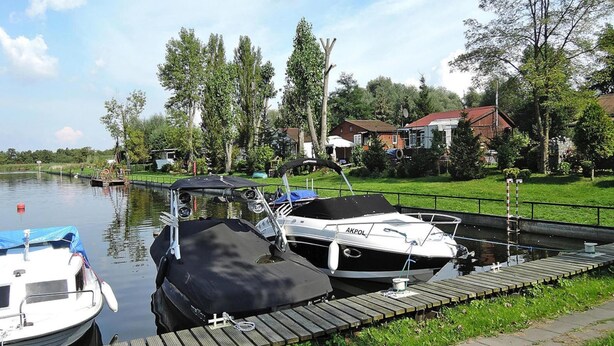 A calm canal with boats docked at wooden piers, surrounded by greenery and residential buildings. - Agriculture - Studios, Borzyslawiec by Lubczyna (Goleniow)