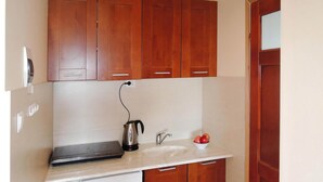 A compact kitchen with wooden cabinets, a white countertop, a kettle, and a bowl of fruit. - Agriculture - Studios, Borzyslawiec by Lubczyna (Goleniow)