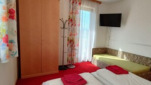 A hotel room with two beds, a wardrobe, a television, and a window with curtains. - Sunny Holiday Apartment on Lake Klopeiner With Balcony and Private Beach (Sankt Kanzian am Klopeiner See)