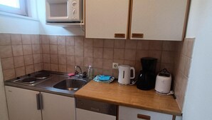 A compact kitchen with a sink, stove, microwave, and a coffee maker. - Sunny Holiday Apartment on Lake Klopeiner With Balcony and Private Beach (Sankt Kanzian am Klopeiner See)