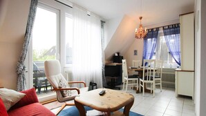Ein modernes Wohnzimmer mit einem roten Sofa, einem Holztisch und einem Essbereich mit weißen Stühlen.
