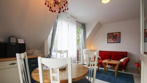 Ein Essbereich mit einem runden Tisch, weißen Stühlen, einem roten Sofa und einer Kronleuchter.