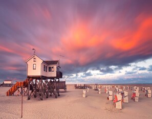 Ein Strandhaus auf Stelzen mit Blick auf den Ozean und Liegestühle.