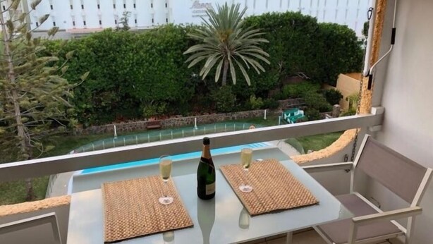 Ein Balkon mit Tisch, zwei Stühlen, einer Champagnerflasche und einem Champagnerglas.