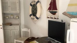 A small room with a television, a chair, a table, and a life preserver decoration on the wall. - Apartment in Sardinia Near Surf Paradise (Palau)