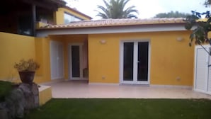 A yellow building with a tiled roof, a glass door, and a small garden area. - Apartment in Sardinia Near Surf Paradise (Palau)