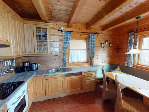 A wooden cabin kitchen with a dining area, wooden cabinets, a sink, and a stove. - Chalet in Wildkogel Near ski Slopes (Neukirchen am Grossvenediger)