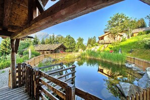 Eine Holzterrasse mit Blick auf einen Teich, vor dem sich ein Berg erstreckt.