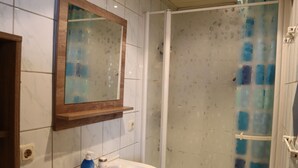 A bathroom with a white sink, a mirror, and a shower with a blue glass door. - Cabin in Brixental by Ski Lift Access (Mittersill)