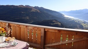 A wooden deck with a table set for breakfast, overlooking a mountainous landscape. - Cabin in Brixental by Ski Lift Access (Mittersill)