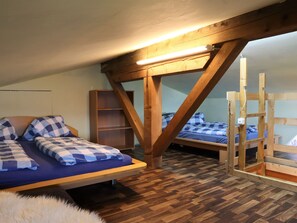 A dormitory room with two bunk beds, wooden beams, a bookshelf, and a fur rug. - Cabin in Brixental by Ski Lift Access (Mittersill)