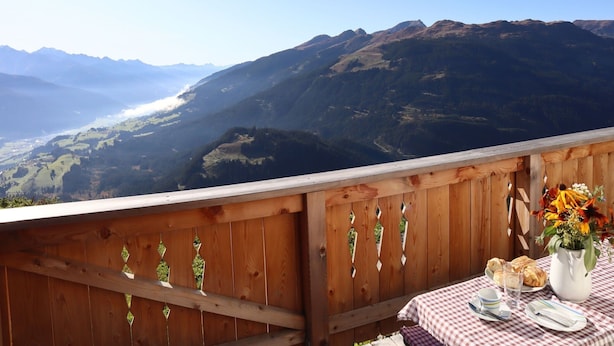 A wooden deck with a table set for dining, overlooking a mountainous landscape. - Cabin in Brixental by Ski Lift Access (Mittersill)