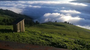 A mountain landscape with a wooden cabin, a road, and a view of snow-capped peaks. - Cabin in Brixental by Ski Lift Access (Mittersill)