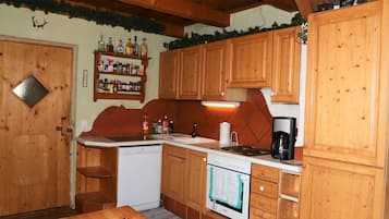 A kitchen with wooden cabinets, a white dishwasher, a stove, and a coffee maker.