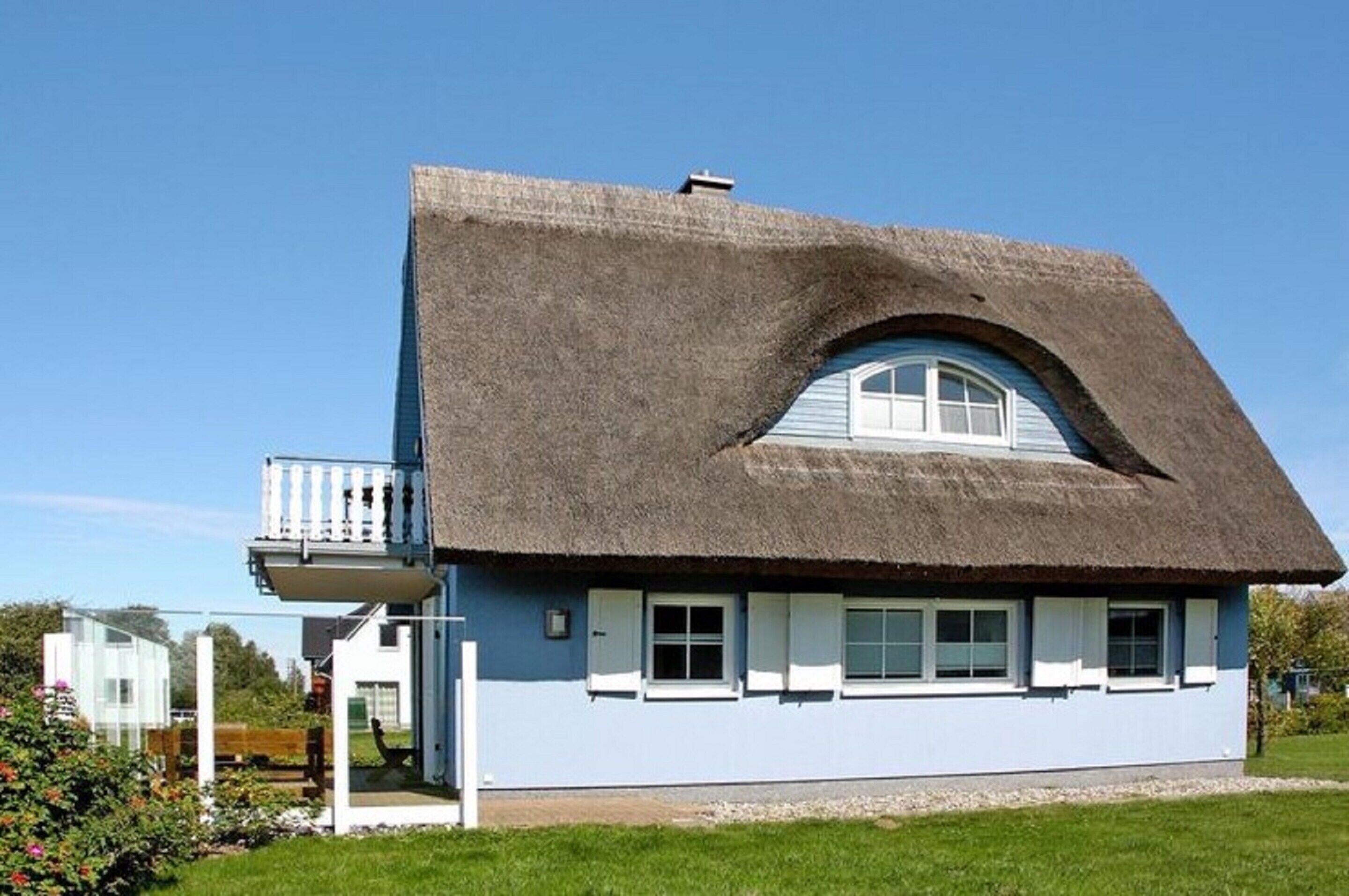 A house with a thatched roof and a balcony.