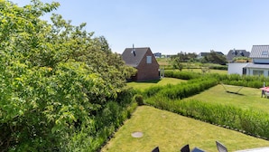 Ein modernes Haus mit Satteldach, umgeben von einem gepflegten Garten mit Rasen und einer Hecke.