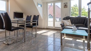 Ein modernes Wohnzimmer mit Essbereich, einer Couch und einem Fernseher.