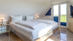 Ein modernes Schlafzimmer mit einem großen Bett, zwei Nachttischen und einem Fernseher an der Wand.