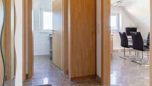 Ein modernes Interieur mit einer Holztür, einem Essbereich mit Stühlen und einer Küche im Hintergrund.