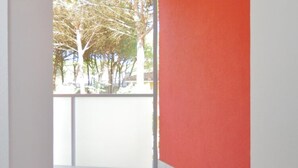 A room with a large window, a red wall, and a white door. - Apartment in Bibione Near the Beach (San Michele al Tagliamento)