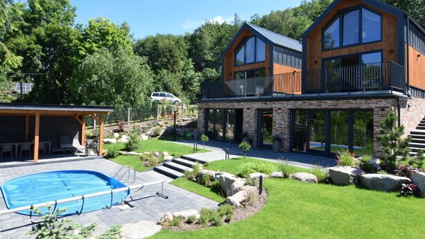 Une maison moderne à deux étages, dotée d’une piscine, d’un espace extérieur aménagé et d’un jardin bien entretenu.