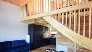 Un intérieur moderne avec un escalier en bois, un canapé bleu et un coin cuisine.