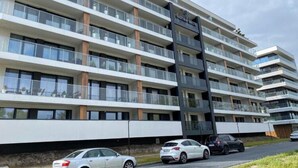 A multi-story hotel with balconies, a prominent entrance, and a parking area with cars. - Holiday Apartment Right Next to the Beach Darlowko (Darlowo)