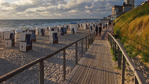 A beach with wooden walkways, beach chairs, and a promenade.