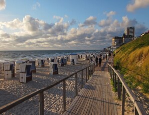 A beach with wooden walkways, beach chairs, and a promenade. - Appartement in Westerland auf Sylt (Sylt)
