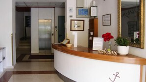 A reception desk with a 'welcome' sign, a potted plant, and a mirror. - Apartment in Garda Near Shopping (Garda)
