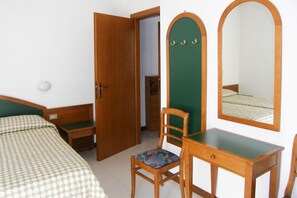 Un dormitorio con una cama, un escritorio de madera, una silla, un espejo y un armario.