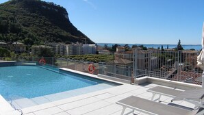 A swimming pool with a view of a mountain and a coastal town. - Apartment in Garda Near Shopping (Garda)