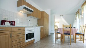 Eine Küche mit Holzausstattung, einem weißen Herd und einem Essbereich mit Holztischen und -stühlen.